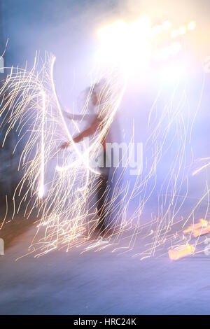 Feuer-Tänzerin mit Benzin (gelbe Flammen) und Feuerwerk (weiße Funken) Stockfoto