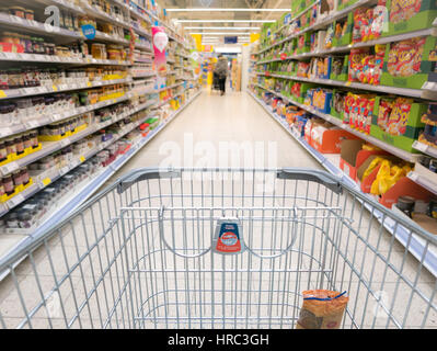 Warenkorb in Gasse des Supermarktes, verschwommene Regal. Stockfoto