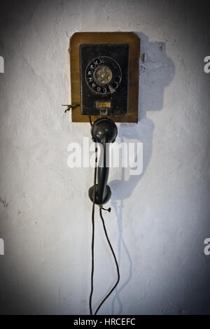 Alte Vintage rotary Telefonzelle mit dem Hörer hängen unten an einer Wand mit Ecke Vignette angebracht Stockfoto