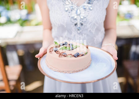 Braut hält leckeren cremigen Kuchen in Händen Nahaufnahme Stockfoto