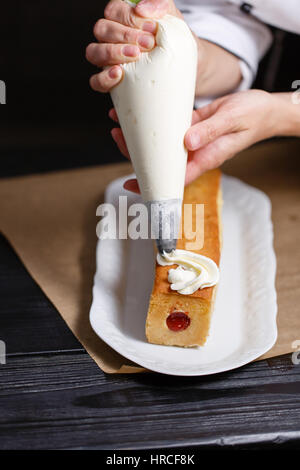 weibliche Hände halten Spritzbeutel gefüllt mit Creme Zuckerguss verzieren Kuchen Stockfoto