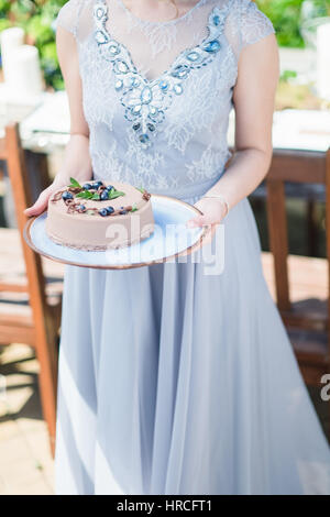 Braut hält leckeren cremigen Kuchen in Händen Nahaufnahme Stockfoto