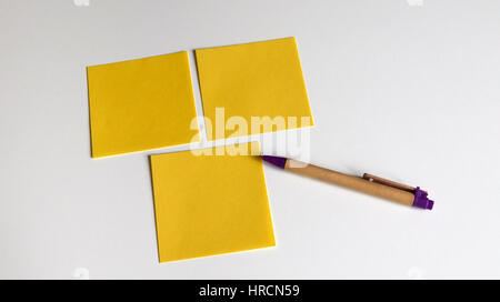 Drei gelbe Noten auf einem weißen Tisch Stockfoto