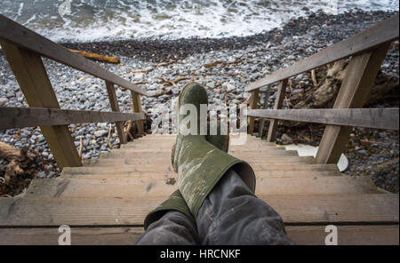 Mann Beine in dreckigen Gummistiefeln nach einem Tag am Strand Stockfoto