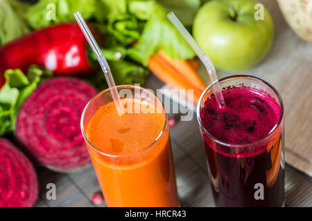 zwei Gläser verschiedene frische Säfte. Rüben und Möhren Säfte auf grauem Holz Hintergrund. Stockfoto