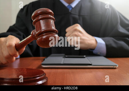 Recht und Gesetz-Konzept. Männlichen Richter in einem Gerichtssaal auffällig die Hammer, arbeiten mit digitalen Tablet Computer Docking-Tastatur auf Holztisch Stockfoto