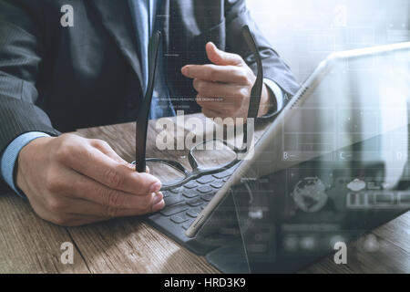 Erfolg Geschäftsmann Hand mit Brillen, digital-Tablette Docking-smart-Tastatur auf Holz Schreibtisch, Ikonen-Grafik Screen-Effekt Stockfoto