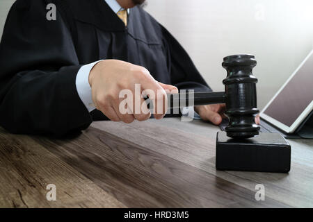 Recht und Gesetz-Konzept. Männlichen Richter in einem Gerichtssaal auffällig die Hammer, arbeiten mit digitalen Tablet Computer Docking-Tastatur auf Holztisch Stockfoto