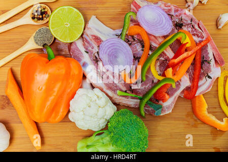 In Scheiben geschnittenen Stücke von rohem Fleisch zum Grillen auf hölzernen Oberflächen, Menü-Kochrezepte. Essen, Steak, Rindfleisch Bbq, Tomaten, Paprika, Gewürze. Stockfoto