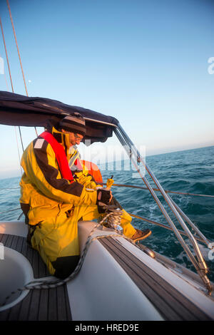 Reifer Mann Kurbeln eine Winde auf Segelboot im Meer Stockfoto