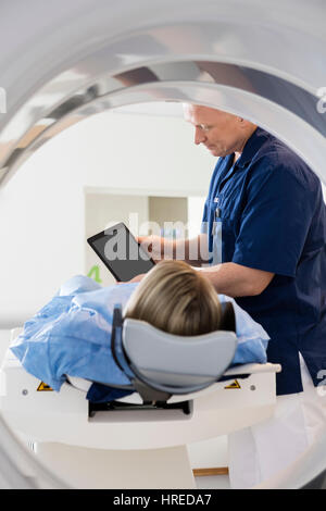 Reifen Doktor mit digitalen Tablet für weibliche Patienten im Krankenhaus CT Scan Stockfoto