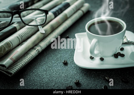 Gläser und Zeitung und Kaffee auf schwarzem Stein Stockfoto