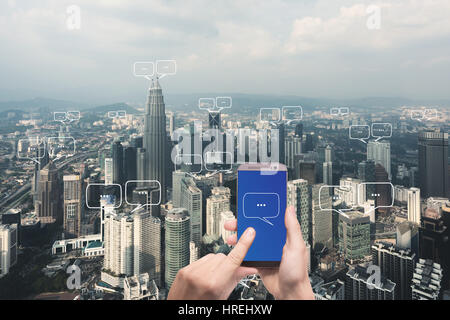 Hand halten Smartphone mit leeren Platz für Text auf Stadt und Bubble Chat für Kommunikation. Technologie und Kommunikationskonzept Stockfoto