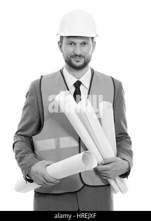 Business Developer. Vertikale monochrome Schuss von einem Geschäftsmann Architekten in einer Warnweste und Bauarbeiterhelm lächelnd in die Kamera Holding Bau Projekt bl Stockfoto