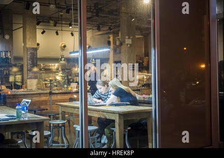 Kunden profitieren von kostenfreiem WLAN im Bean & Bean Coffee Shop in Chelsea in New York auf Dienstag, 28. Februar 2017. Das kostenlose WLAN und die Gemeinschaftstischen Heranziehung die der Coffee-Shop als ein Coworking-Space. (© Richard B. Levine) Stockfoto