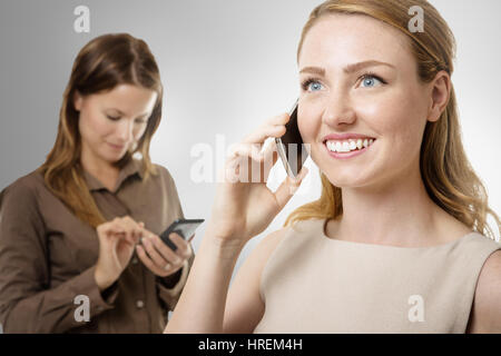 zwei Geschäftsfrauen eins vor anderen sprechen auf dem Handy Stockfoto