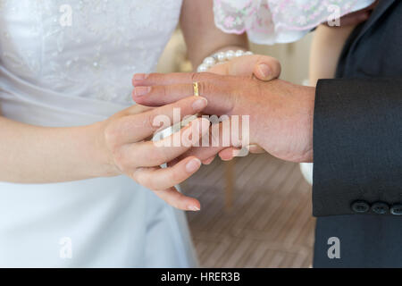 Braut setzt der Bräutigam Hochzeitsringe an den finger Stockfoto
