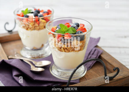 Müsli mit Joghurt und Blaubeere und Erdbeere im Glas auf Holztablett closeup Stockfoto