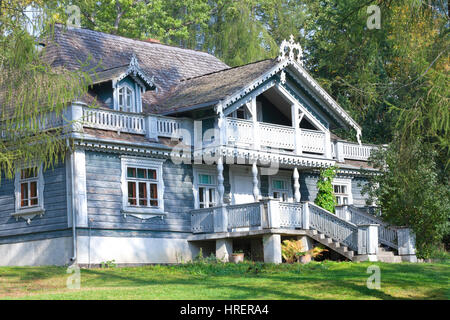 Alte geschnitzte hölzerne Landhaus unter Bäumen an einem Sommertag Stockfoto