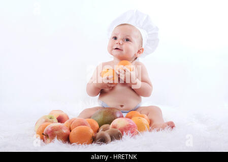 Glückliches Baby in eine Kochmütze mit Früchten Stockfoto