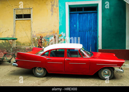Ein Mann zu Fuß in der Nähe von einer klassischen roten Limousine 50' Jahre geparkt vor dem blauen Eingang eines Palastes Stockfoto