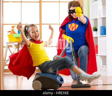 Superhelden kid Mädchen und ihre Mutter Wäsche zusammen im Wohnzimmer. Familymiddle-gealterte Frau und Kind Tochter haben Spaß beim Staubsaugen th Stockfoto