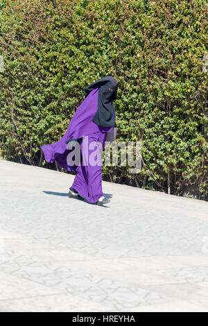 Islamische muslimische Frau tragen violette schwarzen Niqab geht auf Marrakesch Straße. Vertikale erschossen. 15. Februar 2017 Stockfoto