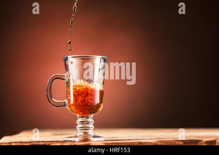 Braun Spritzer Getränk aus blauen Tasse Tee auf einem braunen Holz Hintergrund. Stockfoto