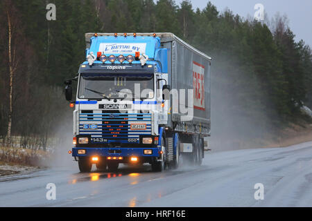 SALO, Finnland - 17. Dezember 2016: Maßgeschneiderte Scania 143 M 500 Sattelschlepper von L. Retva Oy und Curtainsider Anhänger LKW auf nasser Fahrbahn bei Regen in So Stockfoto