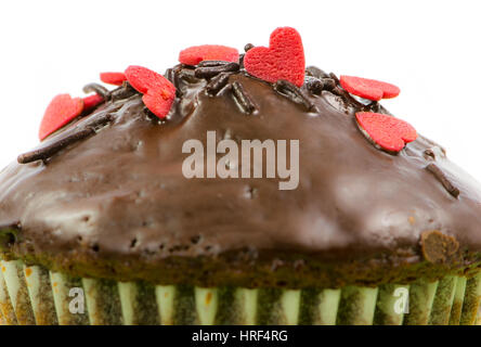 Nahaufnahme von einem isolierten Schoko-Muffin mit roten Zuckerherzen Stockfoto