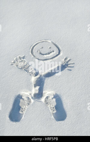 Fußabdrücke bilden Körper, Hände und Beine von diesem lächelnden, glücklicher Mann im Schnee.  Er liebt Schnee und genießt die Natur. Stockfoto
