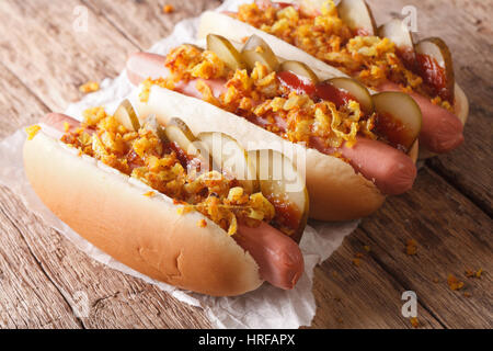 Frische dänische Hot Dogs mit knusprigen Zwiebeln und Gurken hautnah auf dem Tisch. horizontale Stockfoto