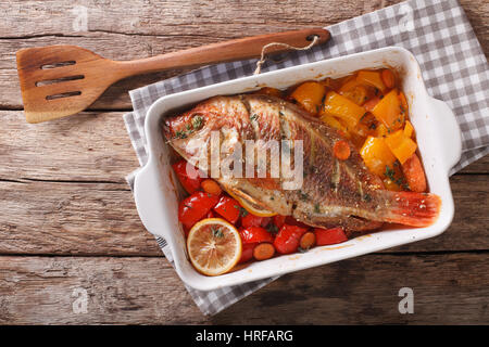 Tilapia-Fisch gebacken mit Paprika, Karotten und Thymian hautnah in Auflaufform auf den Tisch. horizontale Ansicht von oben Stockfoto