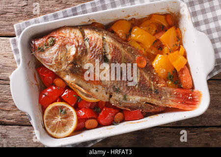 Tilapia gebacken mit Gemüse und Thymian hautnah in Auflaufform auf den Tisch. horizontale Ansicht von oben Stockfoto