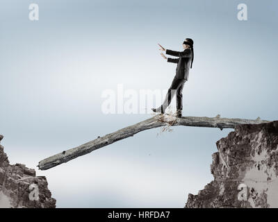 Geschäftsmann mit Blindfolder Augen gehen auf Holzscheit. Mixed-media Stockfoto