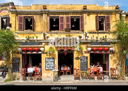 A Straßenszene in Hoi an eine alte Stadt mit Touristen in einem Restaurant oder Café zeigt typische Kolonialarchitektur. Stockfoto