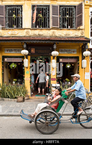 Eine Straße in Hoi an eine alte Stadt mit Touristen in einem Restaurant oder Café zeigt typische Architektur und eine Rikscha Dring letzten Szene. Stockfoto