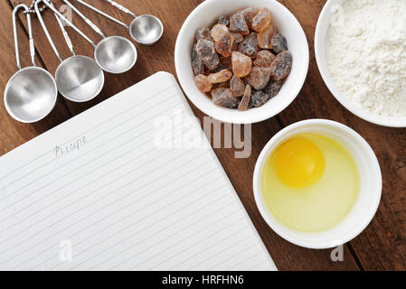 Notizbuch und Zutaten für das Backen auf einem hölzernen Hintergrund Stockfoto