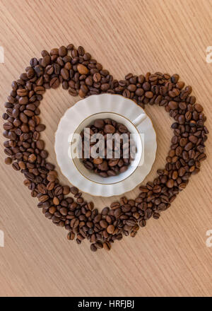 Kaffeetasse und Kaffeebohnen auf einer hölzernen Tisch und Herz-Form aus Kaffeebohnen hergestellt Stockfoto