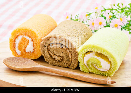 Schweizer Jam Roll auf dem Holzbrett mit Kochlöffel. Stockfoto