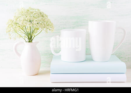 Zwei weiße Tassen Mockup mit Büchern und weißen Blumen im Krug.  Leere Becher mock up für Design-Präsentation. Stockfoto