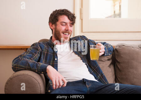 Junger Mann in seinem Wohnzimmer mit einem karierten Hemd und ein Buch Stockfoto