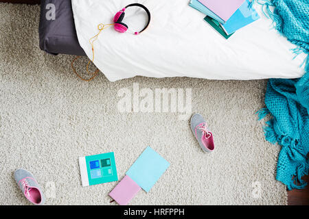 Direkt oberhalb Blick auf Teengirl verstreut unordentliche Schlafzimmer mit Decke, Turnschuhe und Schule Bücher auf Teppich Stockfoto