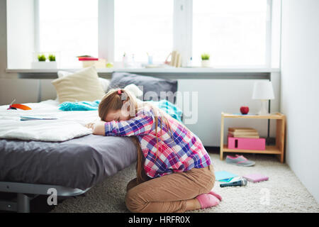Traurige Teen Mädchen sitzen auf Teppich in ihrem gemütlichen Schlafzimmer allein und zu weinen, versteckt ihr Gesicht mit den Händen Stockfoto