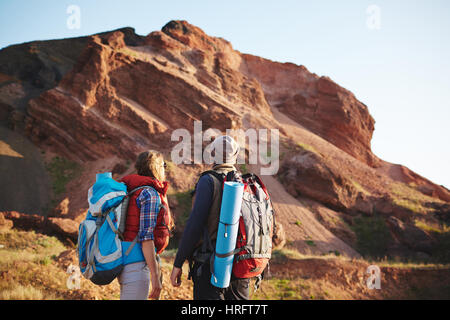 Hintere Ansicht Porträt junges Paar, Mann und Frau, tragen, touristischen Ausrüstung und große Rucksäcke stehen dicht beieinander mit Blick auf Berg, o Reisen Stockfoto