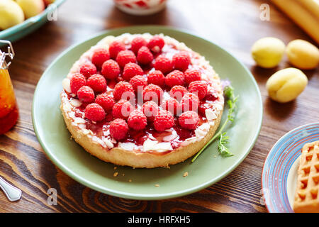 Nahaufnahme der leckere frisch gebackene Mandel Himbeer Torte auf grüne Platte platziert auf Holztisch liegend Stockfoto