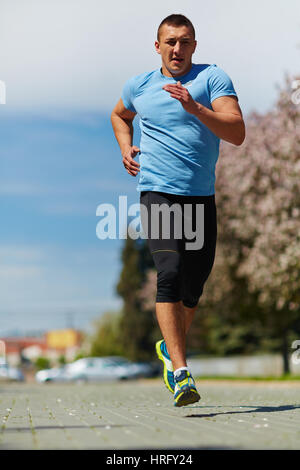 Sportlicher Mann in Sportbekleidung training im Park und Vorbereitungen für den Wettkampf Stockfoto