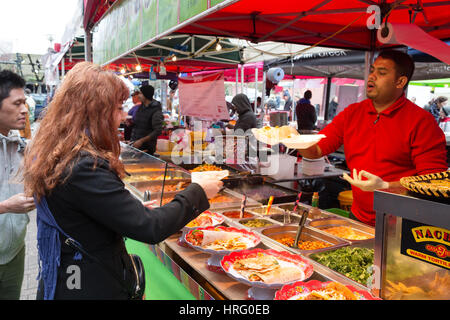 Streetfood; Straßenmarkt; -Eine Frau kauft mexikanisches Essen aus einer Garküche, Portobello Road Market, Portobello Road, Notting Hill, London UK Stockfoto