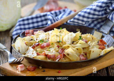 Pasta mit Gebratener Weißkohl und Speck, eine österreichische Spezialität namens "Krautfleckerl", serviert in einer eisernen Pfanne Stockfoto