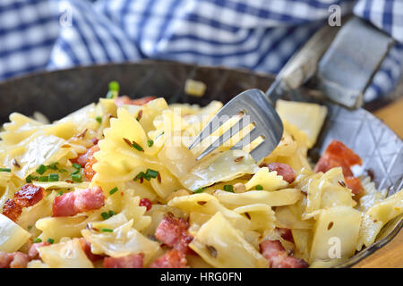 Pasta mit Gebratener Weißkohl und Speck, eine österreichische Spezialität namens "Krautfleckerl", serviert in einer eisernen Pfanne Stockfoto